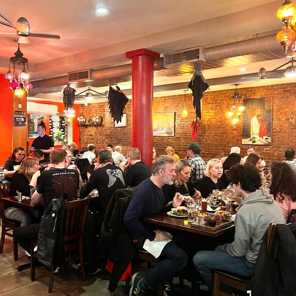Diners enjoying meals at tables in a bustling Turkish restaurant with brick walls and colorful lamps.