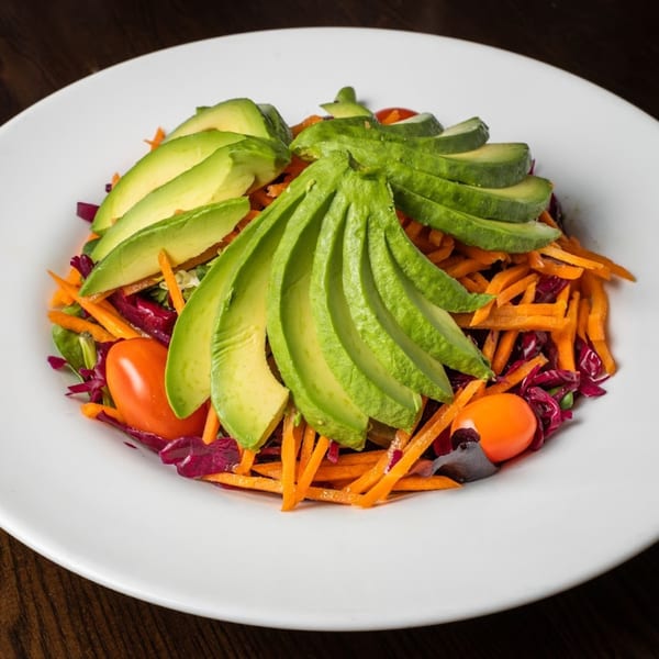 Colorful Turkish salad with sliced avocado, shredded carrots, red cabbage, and cherry tomatoes.