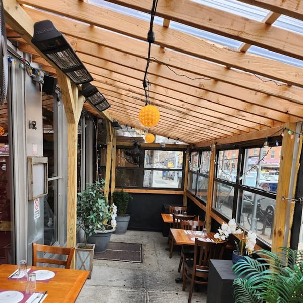 Outdoor dining area at Deniz Turkish Cuisine with wooden beams, heaters, and tables set for guests.