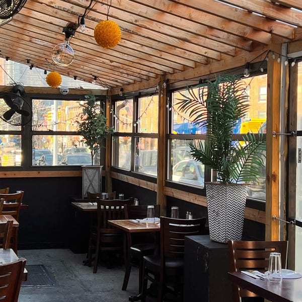 Deniz Mediterranean Turkish Cuisine's outdoor dining area with wooden tables, chairs, plants, and string lights.